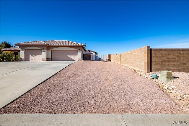 exterior space featuring a tile roof, stucco siding, concrete driveway, an attached garage, and fence