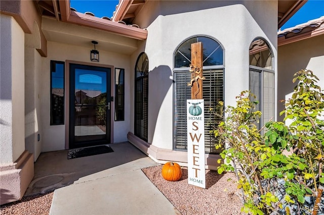 view of exterior entry with a tiled roof and stucco siding