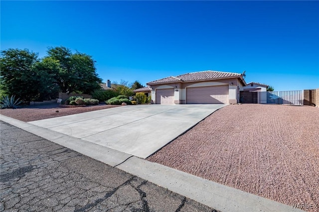 view of front of house with stucco siding, concrete driveway, fence, a garage, and a tiled roof