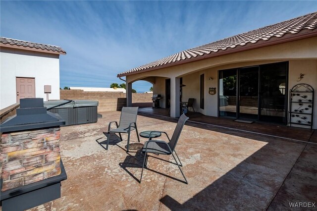 view of patio with a hot tub, fence, and area for grilling