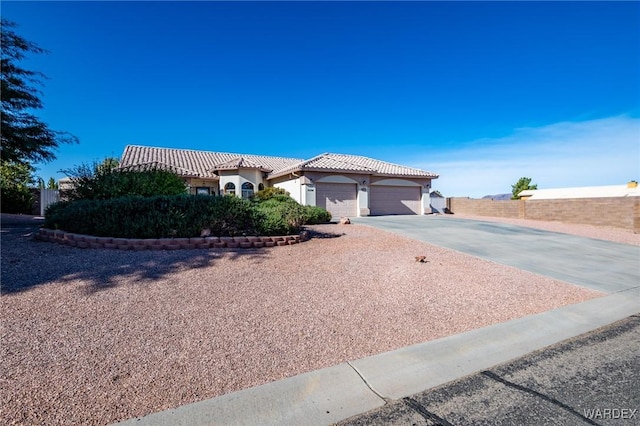 view of front of home featuring a tile roof, stucco siding, fence, a garage, and driveway