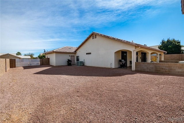 rear view of property featuring central air condition unit, a fenced backyard, a tiled roof, and stucco siding