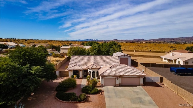 mediterranean / spanish-style house with concrete driveway, a mountain view, a tiled roof, and an attached garage