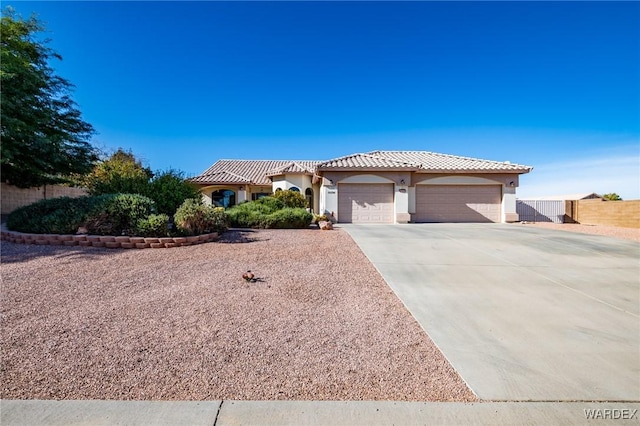 view of front of home featuring stucco siding, an attached garage, fence, driveway, and a tiled roof