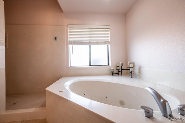 bathroom with a tub with jets and walk in shower