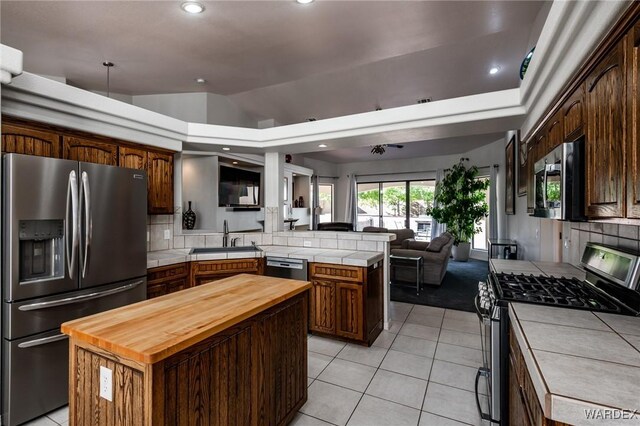 kitchen featuring stainless steel appliances, a peninsula, a kitchen island, a sink, and open floor plan