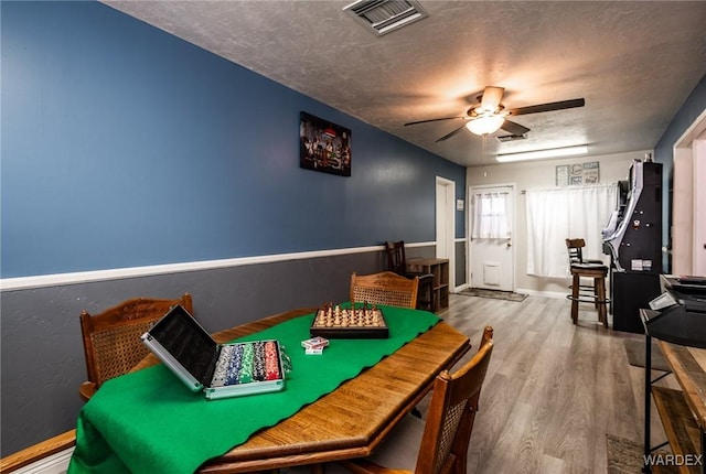 recreation room featuring a ceiling fan, visible vents, a textured ceiling, and wood finished floors