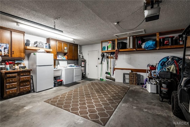 garage featuring washing machine and dryer, water heater, a garage door opener, and freestanding refrigerator