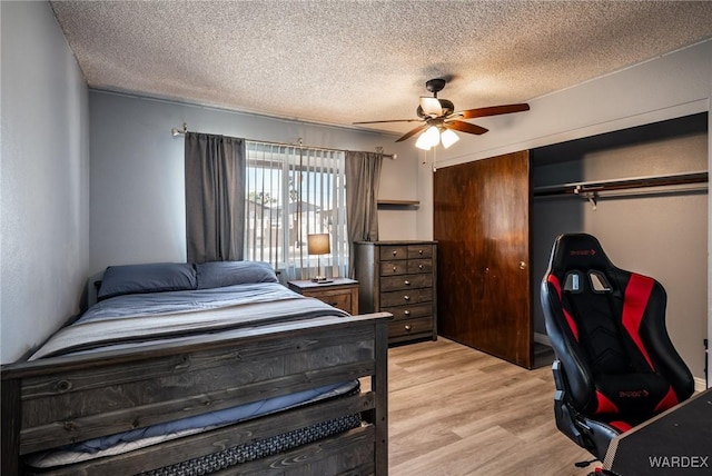 bedroom featuring a ceiling fan, a closet, a textured ceiling, and light wood finished floors