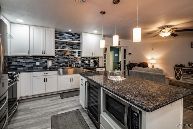 kitchen with white cabinets, stainless steel electric range oven, decorative light fixtures, open shelves, and a sink