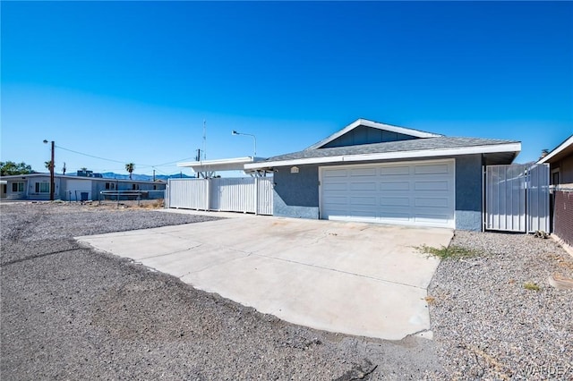 view of front of house with driveway, a garage, a shingled roof, fence, and stucco siding