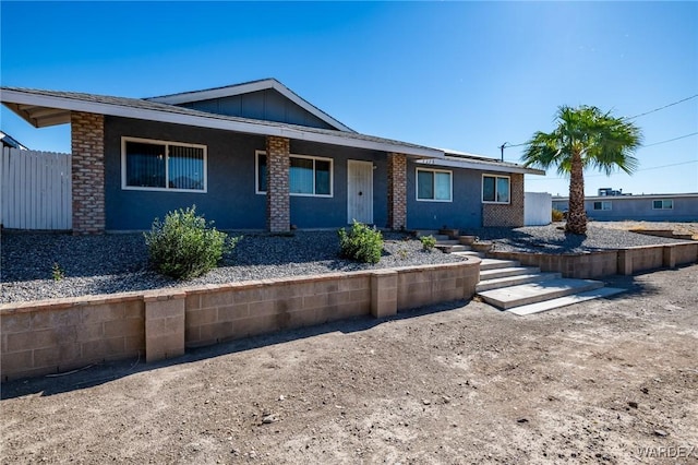 ranch-style home featuring fence, board and batten siding, and stucco siding