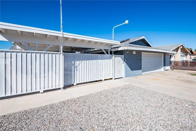 view of front of house with driveway, fence, an attached garage, and stucco siding