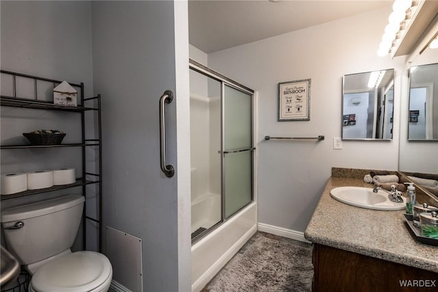 full bath featuring baseboards, vanity, toilet, and bath / shower combo with glass door