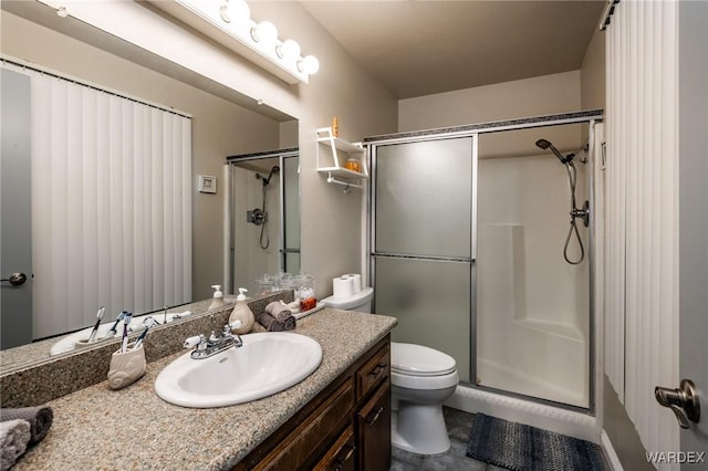 bathroom with toilet, a shower stall, and vanity