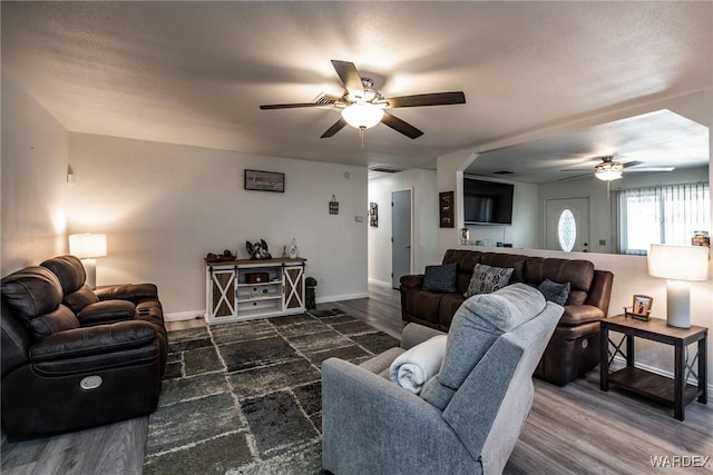 living area with dark wood-style floors, baseboards, and a ceiling fan