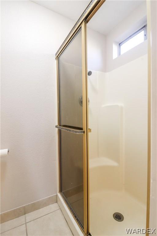 bathroom featuring a stall shower, tile patterned flooring, and baseboards