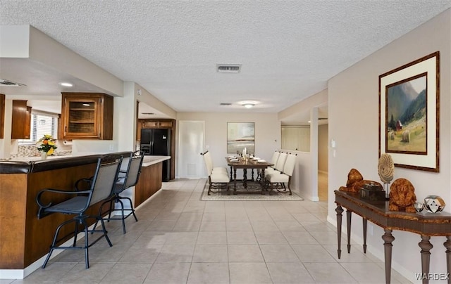 dining room with visible vents, a textured ceiling, and light tile patterned floors