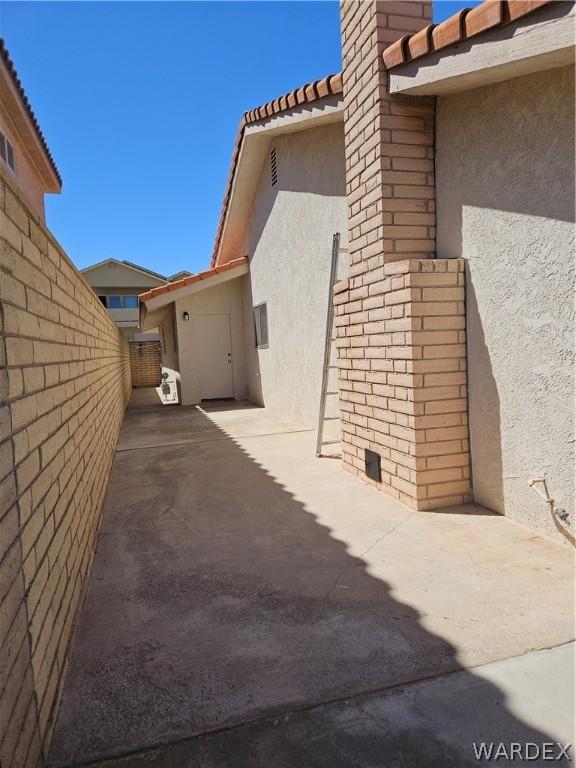 view of property exterior with a tiled roof, a patio area, fence, and stucco siding