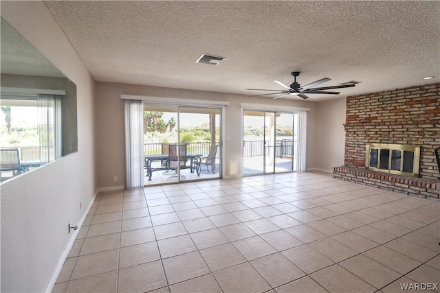 unfurnished living room with a healthy amount of sunlight, light tile patterned floors, a fireplace, and visible vents