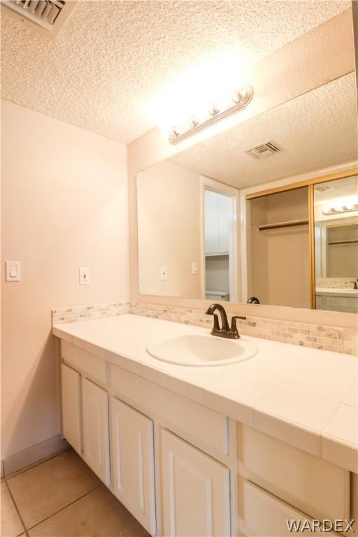 bathroom featuring visible vents, a textured ceiling, vanity, and tile patterned floors