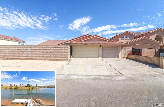 view of front of house with a garage, a water view, driveway, and a tiled roof