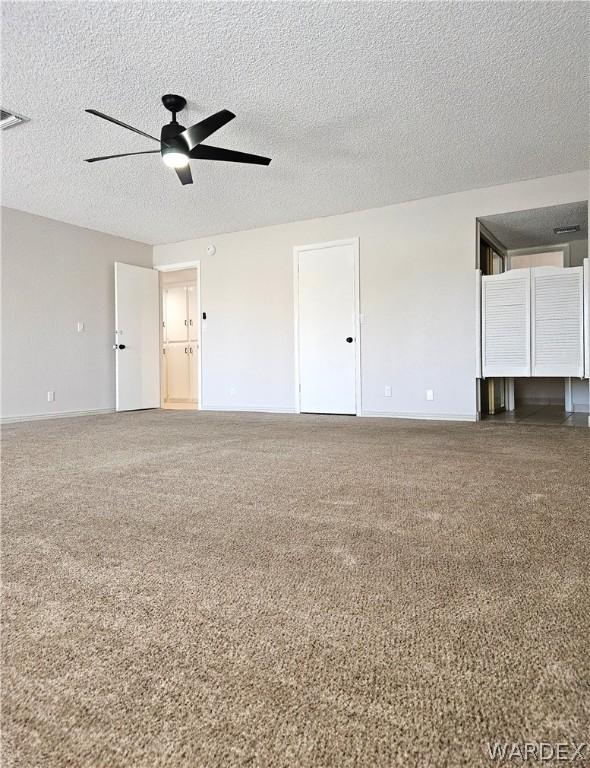 carpeted spare room with a textured ceiling, a ceiling fan, and baseboards