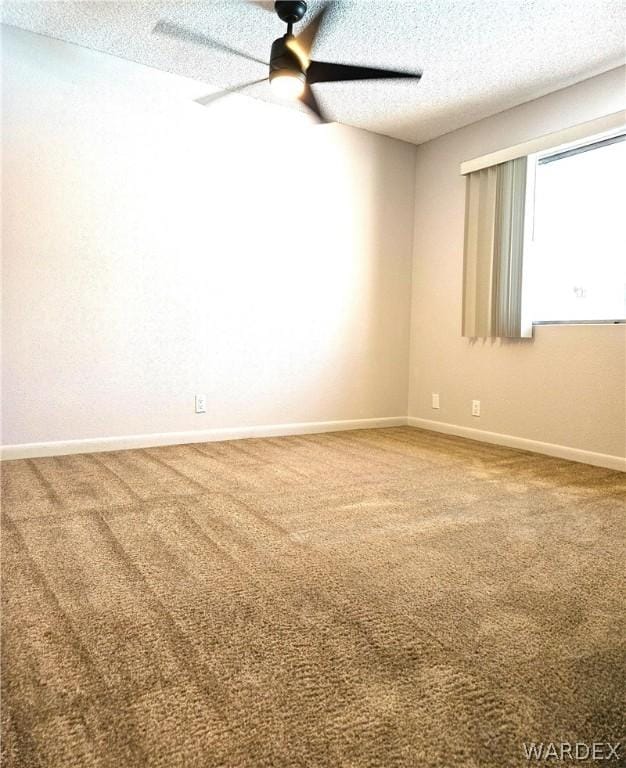 spare room featuring carpet, baseboards, ceiling fan, and a textured ceiling