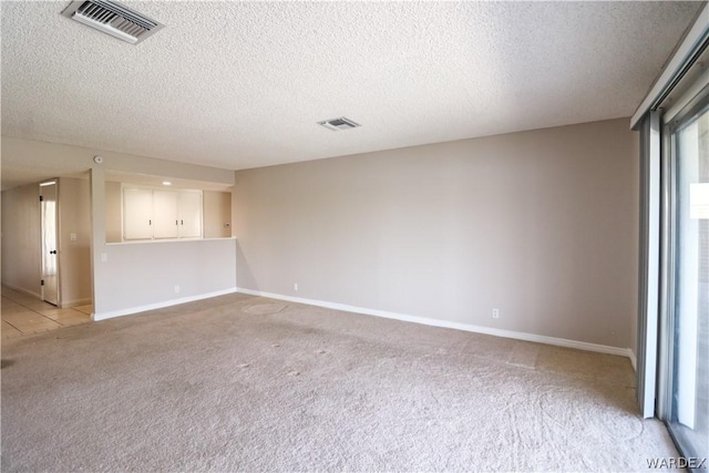 spare room featuring light carpet, visible vents, and a textured ceiling