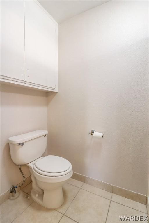 half bathroom with toilet, tile patterned flooring, and baseboards