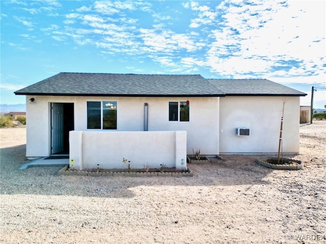 back of house featuring a shingled roof and stucco siding