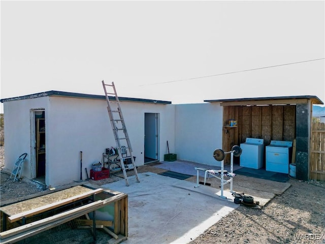 rear view of house featuring a patio area, washing machine and clothes dryer, and stucco siding