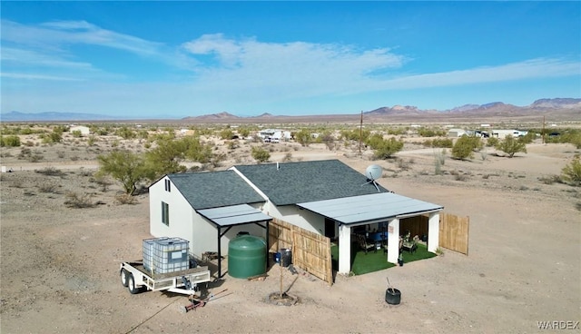 exterior space with stucco siding, a shingled roof, a mountain view, and view of desert