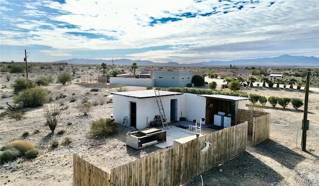 exterior space featuring fence, a mountain view, and stucco siding