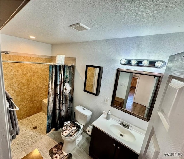 bathroom featuring a textured ceiling, a textured wall, toilet, visible vents, and tiled shower