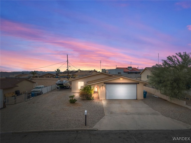 view of front of house with concrete driveway, an attached garage, fence, and stucco siding