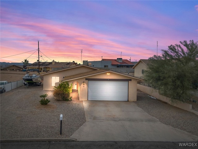 view of front of property featuring stucco siding, concrete driveway, a garage, and fence