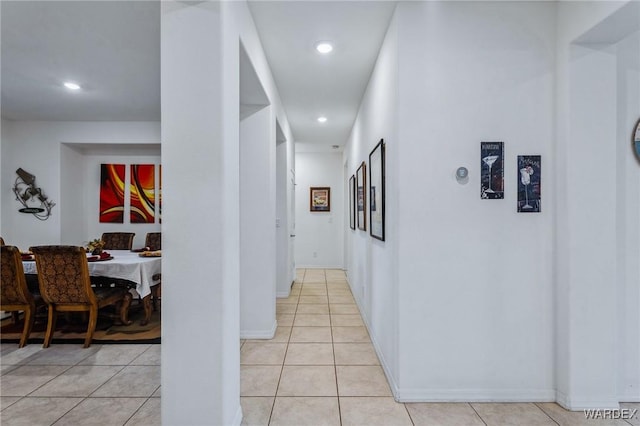 corridor featuring light tile patterned floors, baseboards, and recessed lighting