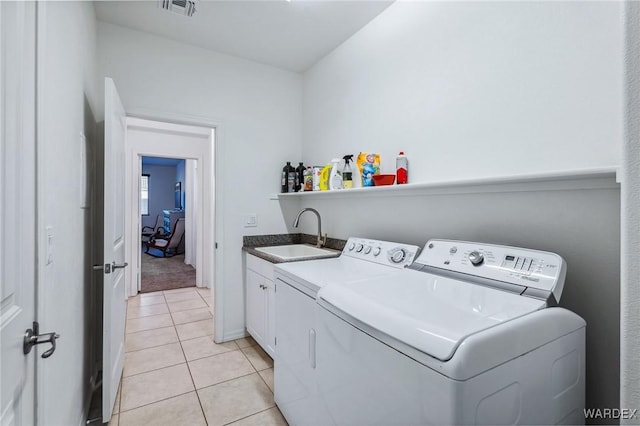 washroom featuring light tile patterned flooring, a sink, visible vents, independent washer and dryer, and cabinet space