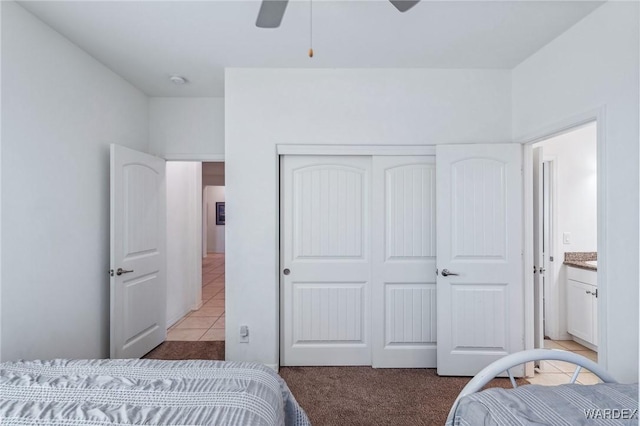 bedroom with a ceiling fan, a closet, light carpet, and light tile patterned floors