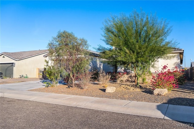 obstructed view of property with driveway, an attached garage, and stucco siding