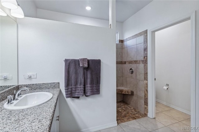 full bath featuring tile patterned flooring, baseboards, a walk in shower, and vanity