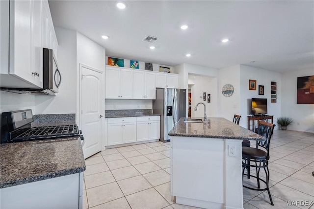 kitchen featuring stainless steel appliances, a kitchen island with sink, a sink, and white cabinetry