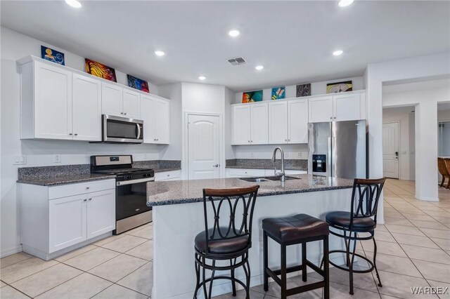 kitchen featuring a kitchen island with sink, appliances with stainless steel finishes, white cabinets, and a sink