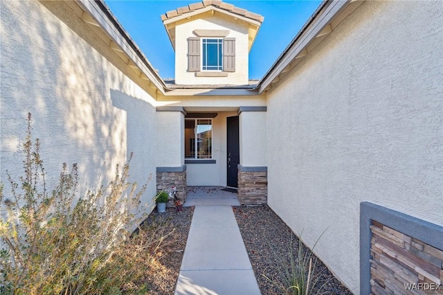 doorway to property featuring stone siding and stucco siding