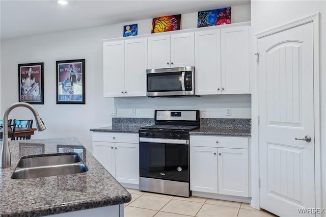 kitchen with white cabinets, light tile patterned floors, stainless steel appliances, and a sink