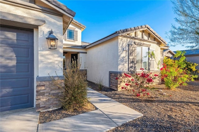 entrance to property featuring a garage and stucco siding