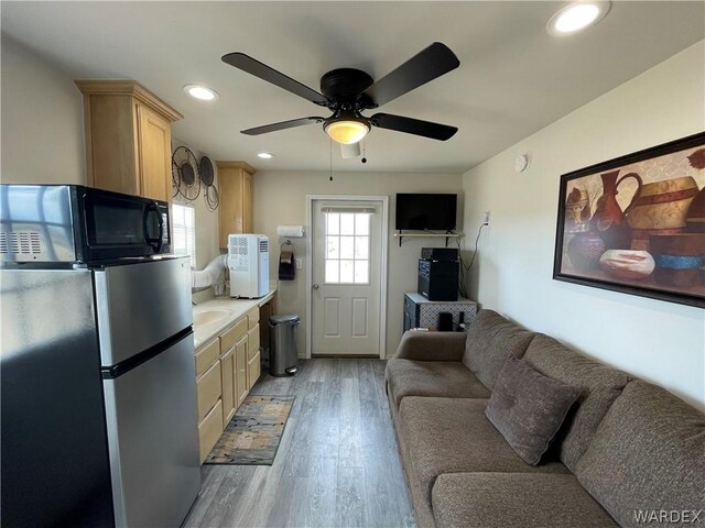 kitchen featuring light countertops, light brown cabinetry, freestanding refrigerator, open floor plan, and black microwave