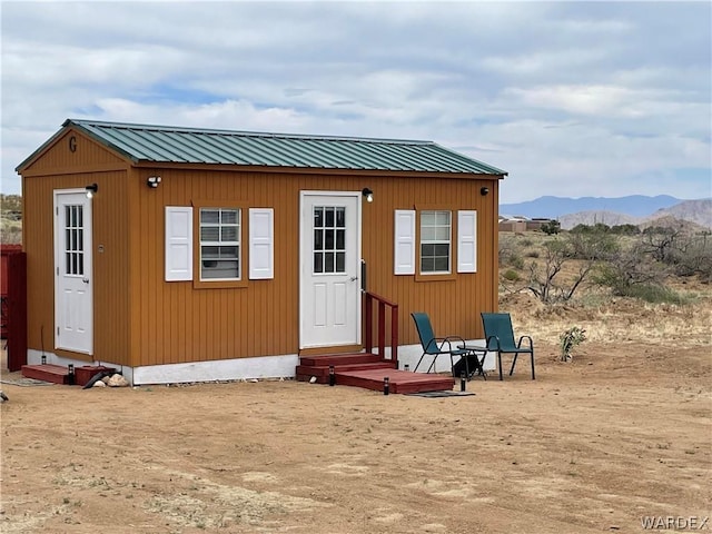 view of outdoor structure with entry steps, a mountain view, and an outbuilding