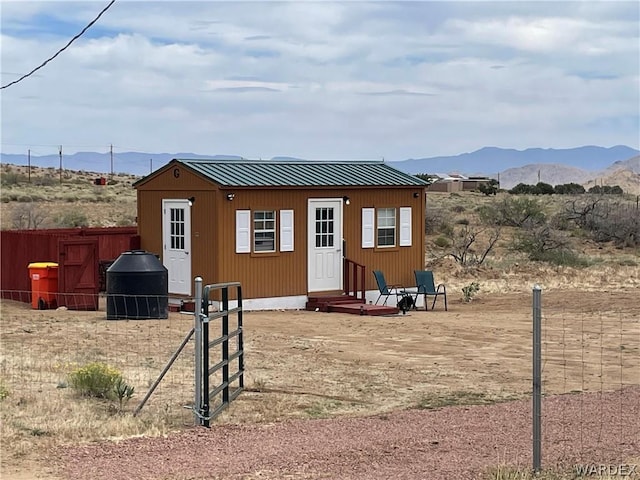 rear view of house with metal roof, a mountain view, a standing seam roof, and fence